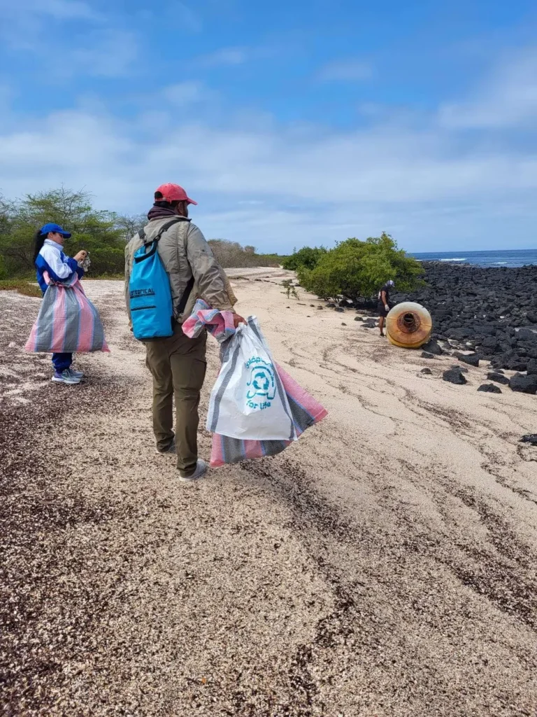 A volunteer carrying bags of collected waste along the beach